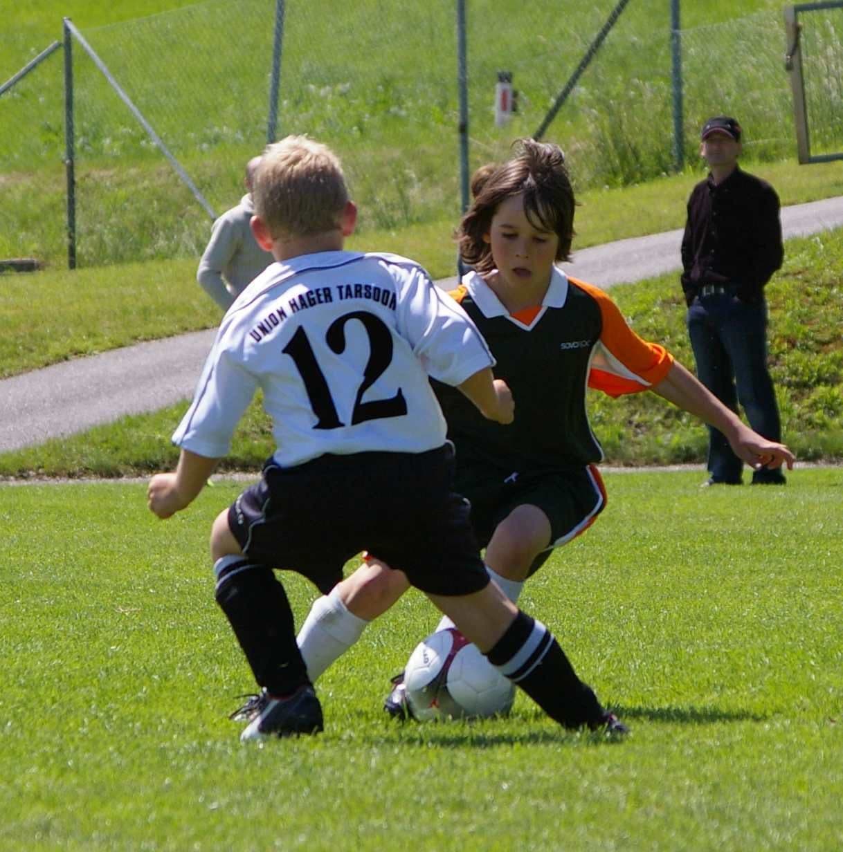 Youth footballers contesting the ball on a grass pitch