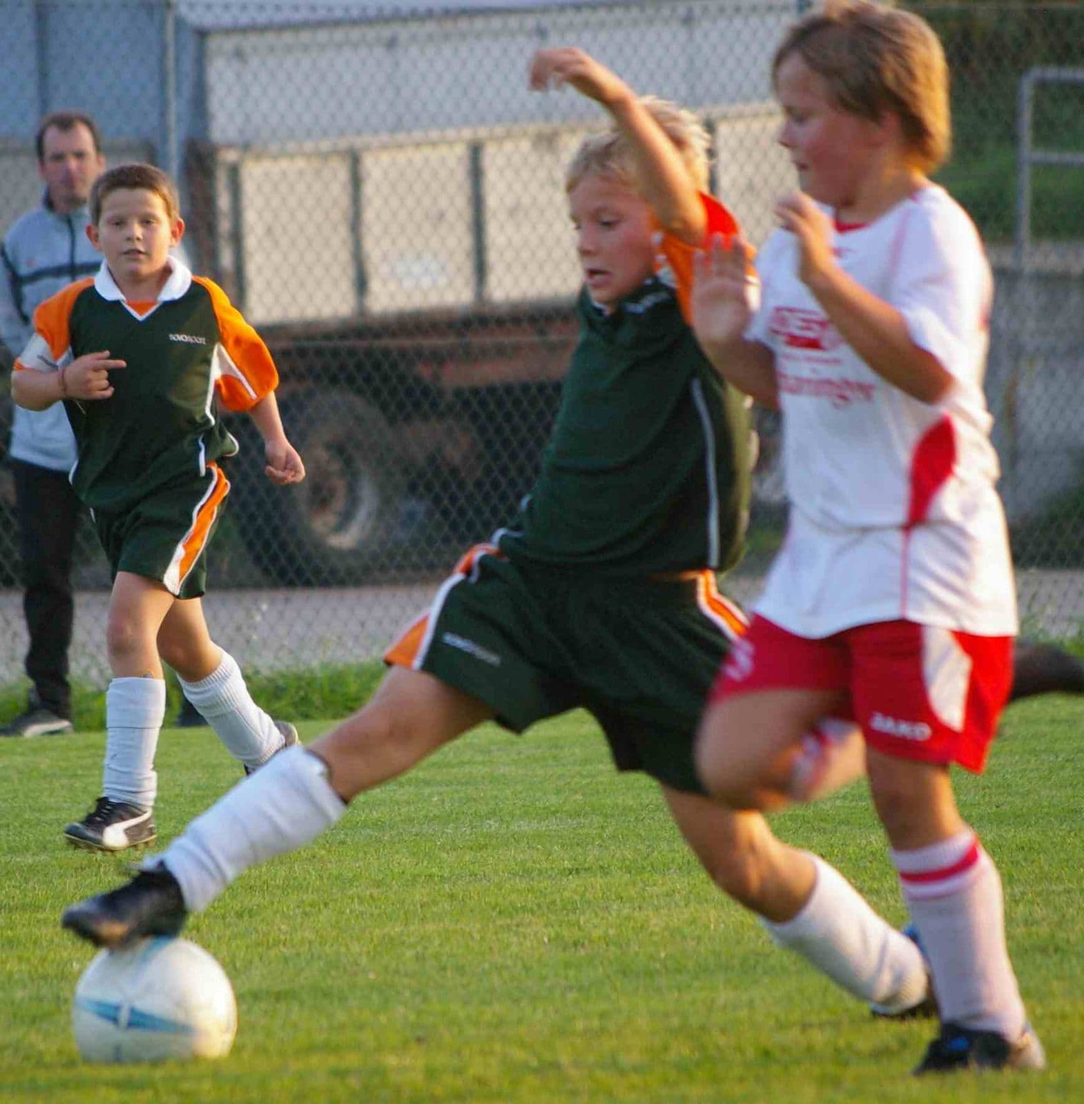 Youth players contesting a football on a grass pitch