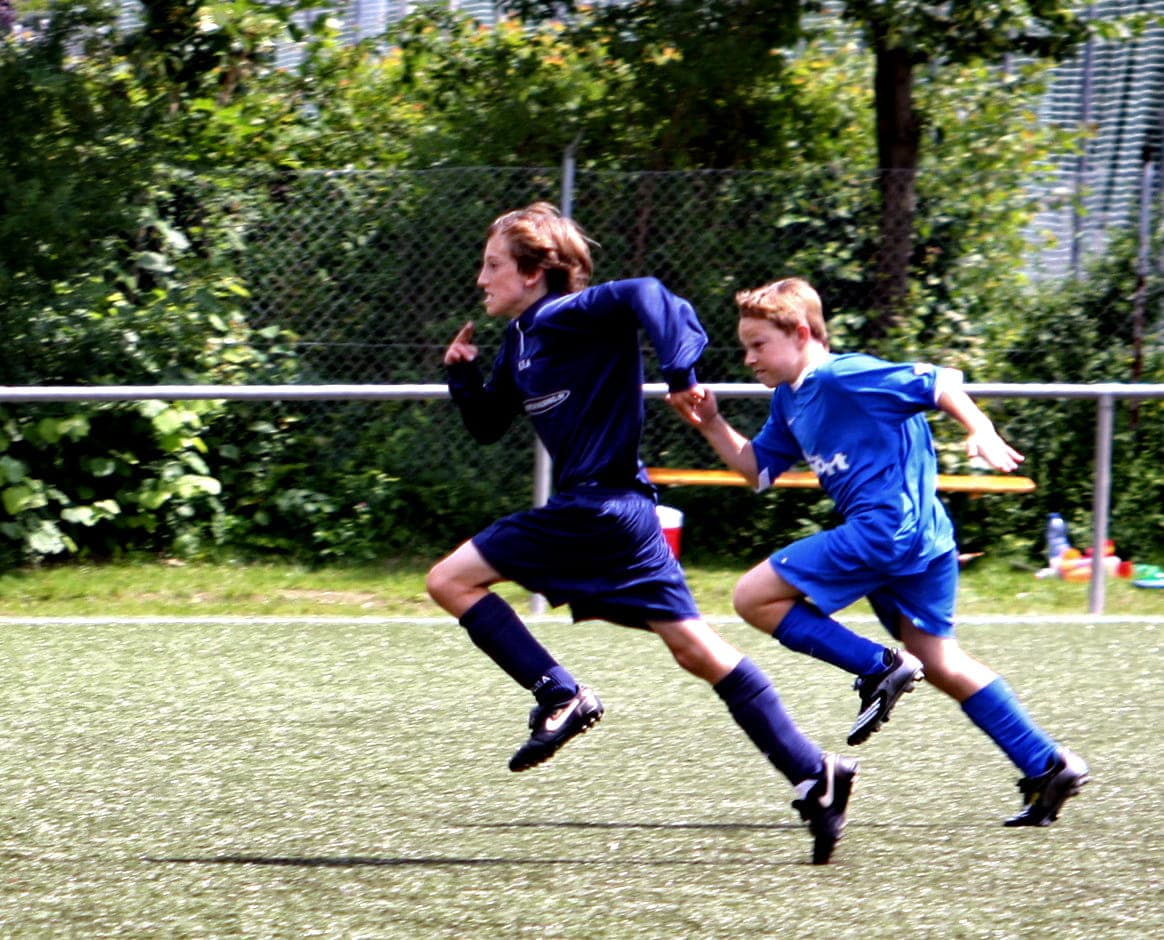 Two footballers sprinting towards the ball during a match