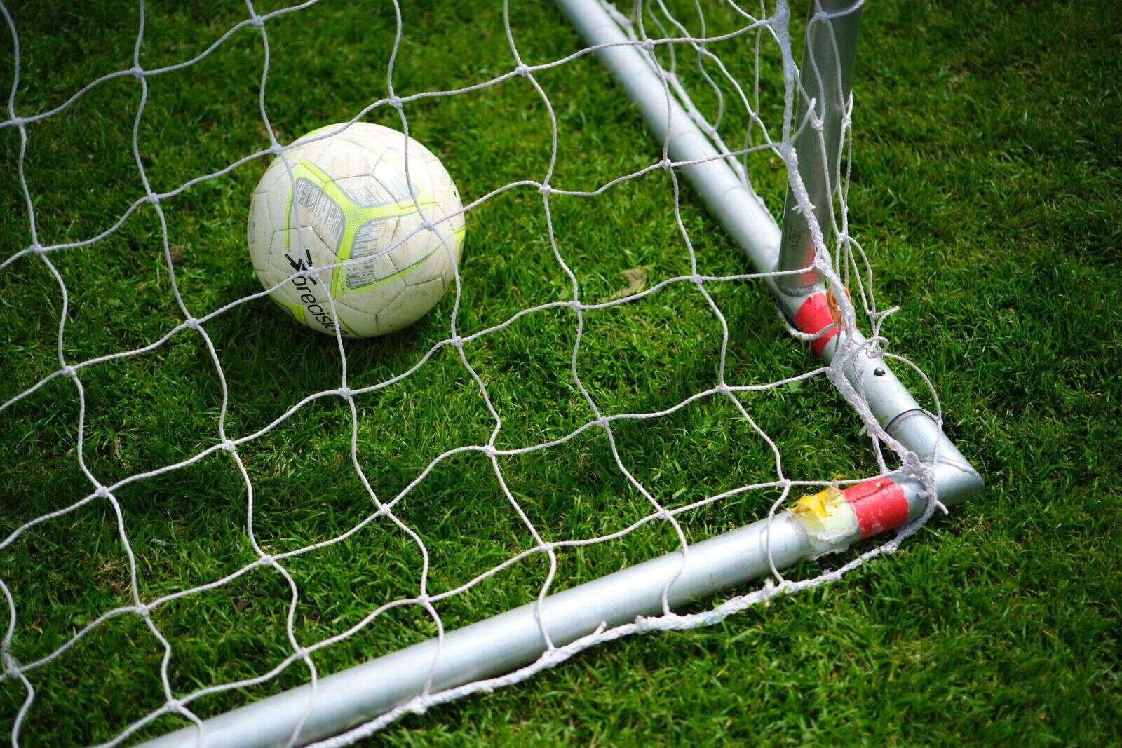 Empty football field with goal under clear sky