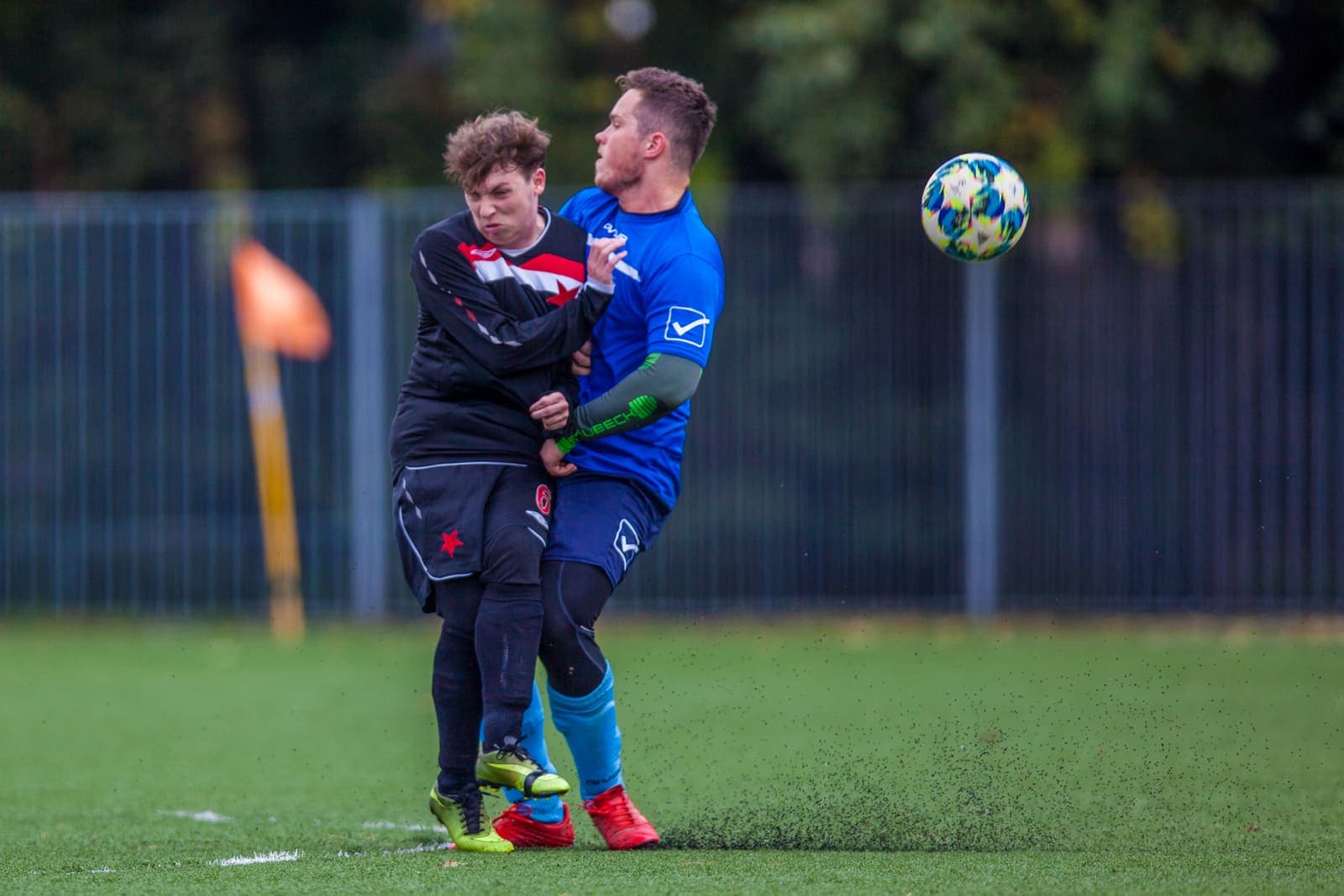 Two youth footballers contesting an aerial ball on an artificial pitch
