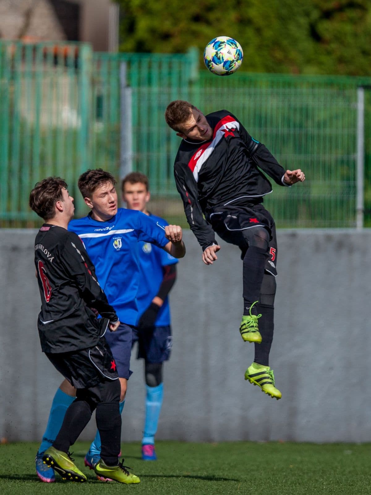 Youth footballer jumping to contest a high ball during a match