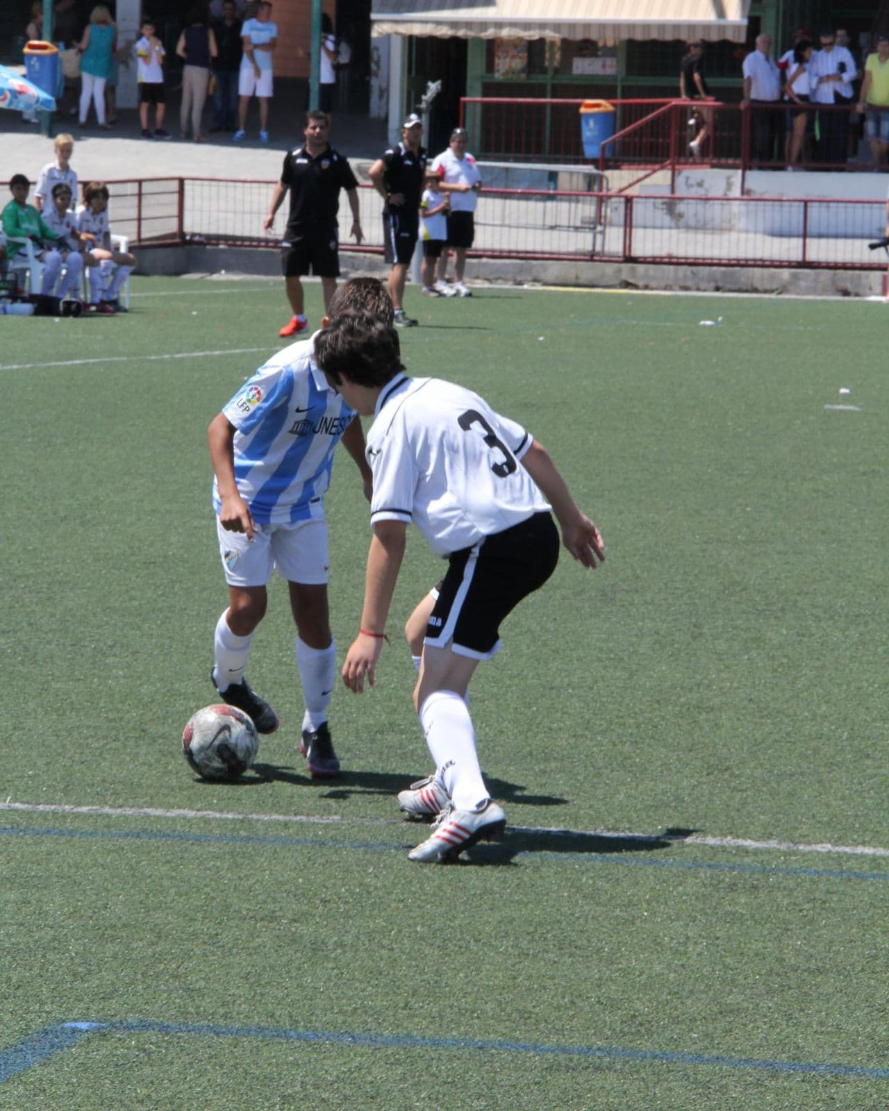 Two youth players on a futsal court with a football